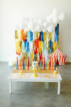 a circus themed birthday party with balloons and confetti on the table, including a cake