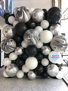 black, white and silver balloons are arranged in the shape of a ballon bouquet