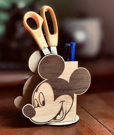 a mickey mouse pen holder with scissors and pens