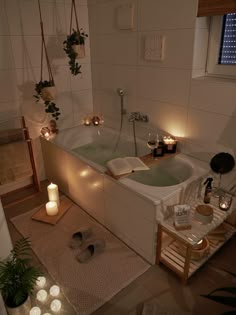 a bathtub with candles on the floor next to it and an open book in front of it