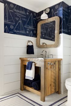 a bathroom with blue and white wallpaper on the walls, wooden sink vanity and mirror