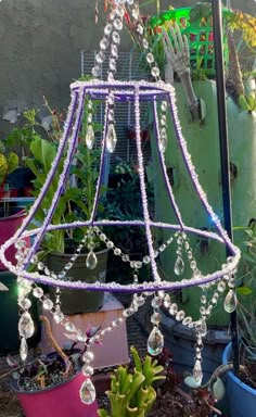 a purple chandelier hanging from a ceiling in front of some potted plants