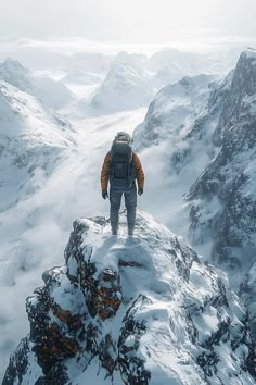 a man standing on top of a snow covered mountain looking down at the valley below