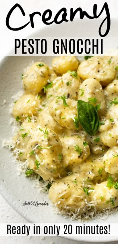 a white plate topped with pasta covered in pesto gnocchi sauce and garnished with parsley