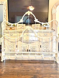 an ornate white bed frame in front of a flat screen tv