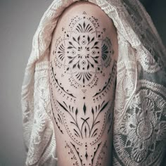 a woman's arm with an intricate tattoo design on the back of her shoulder