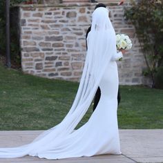 the bride and groom are walking together in their wedding gowns, veils over their heads