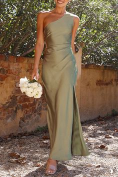 a woman in a long green dress holding a white bouquet and smiling at the camera