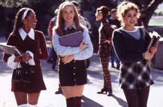 three girls in school uniforms are walking down the street