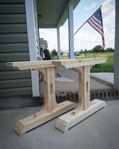 a wooden table sitting on the side of a house with an american flag in the background