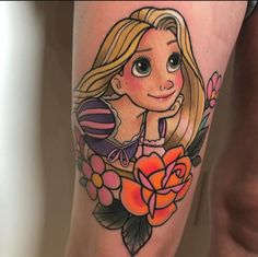 a woman's leg with a cartoon character on it and flowers in the background