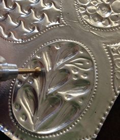 a person is painting the inside of a metal tray with silver paint and an acrylic brush