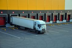 a semi truck parked in front of a storage building with red doors and yellow trim