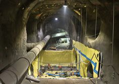 the inside of a tunnel that is under construction with pipes and yellow tarp on it