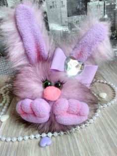 a purple stuffed animal with a pink bow on it's head sitting on a table