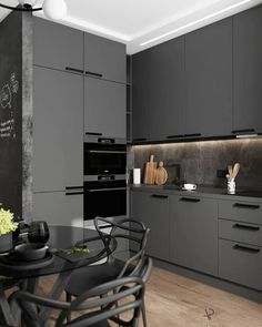 a black and white kitchen with lots of counter space, chairs, cabinets and a chalkboard on the wall