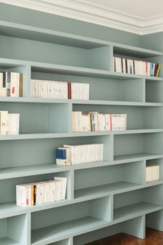 an empty bookshelf in a room with hard wood flooring and blue walls