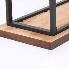 a wooden table with metal legs and a square top on a white surface, viewed from the bottom