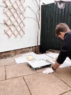 a man in black shirt and white gloves working on cement