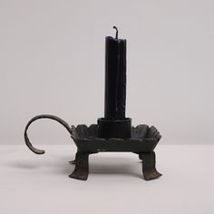 a black candle holder with an animal design on the front and back sides, sitting on a white surface