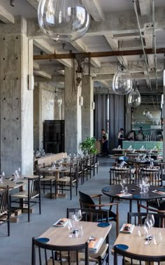 an empty restaurant with wooden tables and chairs, hanging chandeliers over the dining area