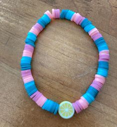 a bracelet made out of strips of paper with a lemon on the end and a button in the middle