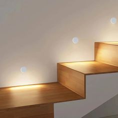 some lights that are on the side of some stairs in a room with white walls