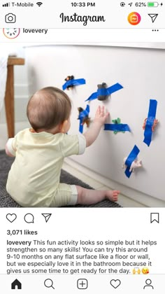 a baby playing with blue tape on the wall in front of an instagram page