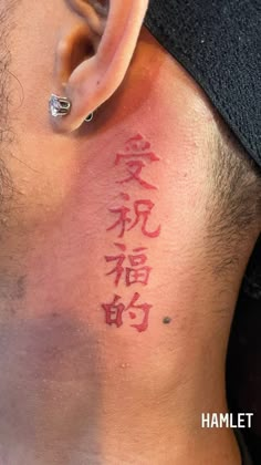 the back of a man's neck with chinese writing on it and an ear piercing