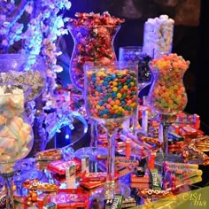 a table topped with lots of candy and candies next to tall glass vases