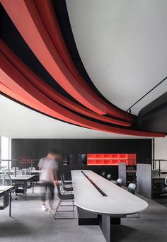 an office with black and red lines hanging from the ceiling, along with people working at desks