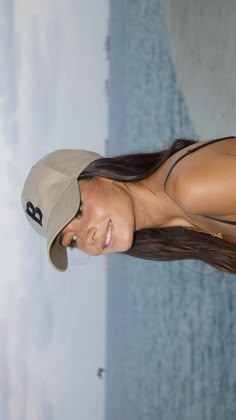 a woman wearing a hat and posing for a photo in front of a blue wall