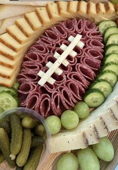 a football shaped cheese board with grapes, pickles and crackers