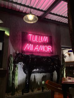 a neon sign that says tulmum manor on the side of a wall next to a cow statue