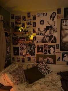 an unmade bed with lots of posters on the wall