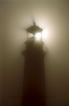 a lighthouse in the fog with a light shining on it's top and bottom