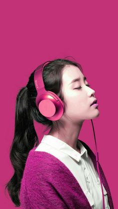 a woman with headphones on her ears looking up to the side, against a pink background