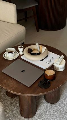 a wooden table topped with a laptop computer next to a cup of coffee and saucer