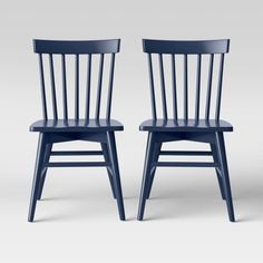 two blue chairs sitting next to each other on a white surface with one chair facing the camera