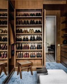 a closet with wooden shelves filled with lots of shoes and foot stools next to an open door