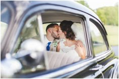 a bride and groom kissing in the back seat of a car, taken from inside