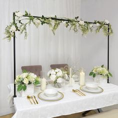 the table is set with white flowers and gold place settings for two people to sit at