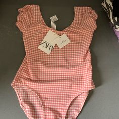 Adorable Light Orange And White Checked Print With Small Ruffles On The Cap Sleeves. Cap Sleeve Swimsuit, Pink Cotton Bodysuit For Beach, Playful Spring One-piece Bodysuit, Playful One-piece Bodysuit For Spring, Playful Spring Bodysuit, Zara Summer Bodysuit For Beach, Zara Summer Beach Bodysuit, Cute Summer Bodysuit For Vacation, Cute Summer Vacation Bodysuit