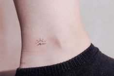 a small sun and moon tattoo on the side of a woman's right ankle