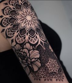 a woman's arm with black and white tattoos on it, showing the intricate design