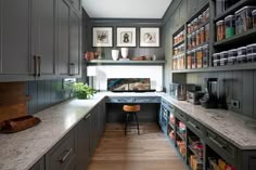 a kitchen with gray cabinets and white counter tops is pictured in this image, there are pictures on the wall