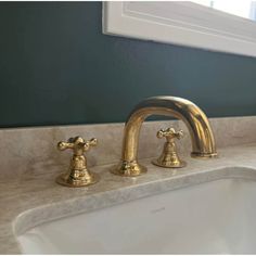 two golden faucets on a marble sink in a blue and white bathroom with green walls