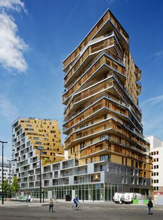 people are walking in front of a tall building with balconies on the sides