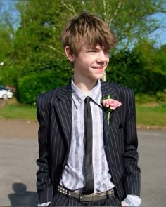 a young man in a pinstripe suit with a flower on his lapel