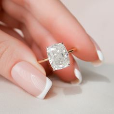 a woman's hand holding an engagement ring with a large diamond in the middle